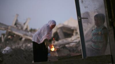 A Palestinian woman makes coffee on a fire outside her makeshift shelter near the ruins of her house, which witnesses said was destroyed during the Israeli offensive, in Al Mughraga village in the south of Gaza City. Mohammed Salem / Reuters