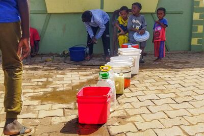 Displaced Sudanese men and children fill jerrycans and buckets with drinking water in Wad Madani, south of Khartoum. AFP