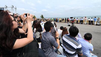 Spectators watch an Airbus A350 perform a flypast during the Singapore Airshow. Roslan Rahman / AFP