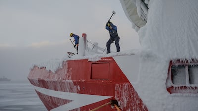 Crew members use hammers to de-ice the bow of the Sarfaq Ittuk ferry, in Sisimiut, Greenland. AFP