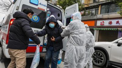 Fully protected medical staff help a patient off the ambulance outside the hospital in Wuhan, Hubei province, China. EPA