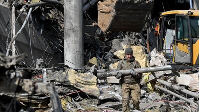 A Ukrainian serviceman carries a fragment of a rocket outside a building in Kyiv that was destroyed by Russian shelling. AFP