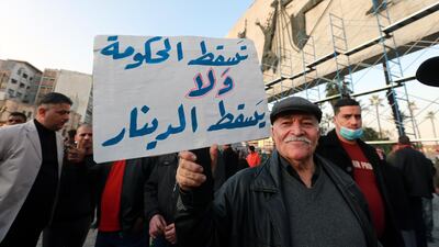 An Iraqi protester carries a placard denouncing the devaluation of the country's currency during a demonstration at Tahrir Square in central Baghdad, Iraq, on December 21, 2020. EPA