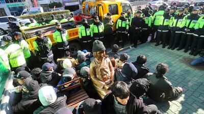 South Korean activists stage a protest around a statue of a teenage girl symbolising former ‘comfort women’ forced into sexual slavery by Japan during the Second World War, which they tried to set up outside the Japanese consulate in Busan. Yonhap / AFP