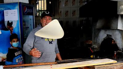 Abu Shadi tosses the flatbread dough to thin it before garnishing. AFP