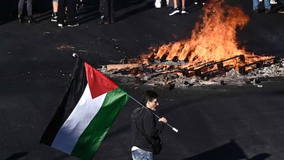 A protester carries a Palestinian flag past a fire burning in Genova. EPA