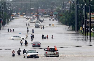 This photo taken on August 27, 2017 shows people walking through the flooded waters of Telephone Rd in Houston battled with tropical storm Harvey and resulting floods. Thomas B Shea / AFP
