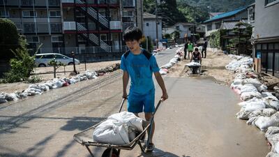 A boy moves sandbags to place outside properties as floodwater flows down a road in Yanohigashi. Getty Images