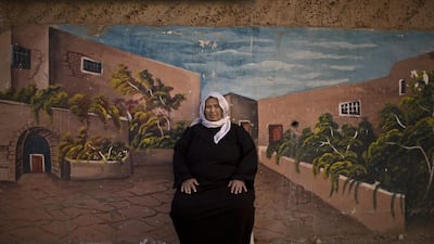 Palestinian refugee Jamilah Shalabi, 70, in front of a wall painted with a mural in the West Bank refugee camp of Jenin, where she has lived since she was 4 years old when she and her parents were forced to leave their home in Zarin village.