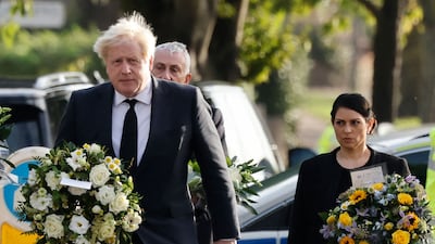 UK Prime Minister Boris Johnson and Home Secretary Priti Patel carry floral tributes to the scene of the fatal stabbing of Conservative lawmaker David Amess in south-east England on Saturday. AFP