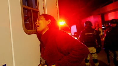 A Venezuelan migrant waits for her injured husband as Mexican firefighters remove the injured from the National Migration Institute. Reuters