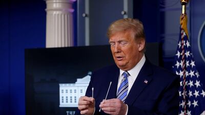 US President Donald Trump compares a swab for coronavirus disease testing with regular cotton swabs during the daily coronavirus task force briefing at the White House in Washington. Reuters