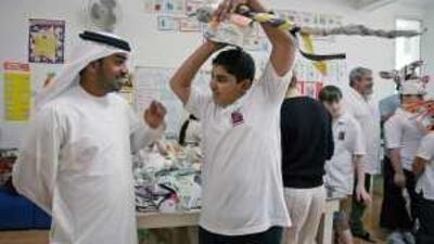 Eid al Shamsi shows his father Saif a mask made for him by the Mora Brothers, two Cuban artists in town for the Womad festival, at the Future Centre for Special Needs in Abu Dhabi.