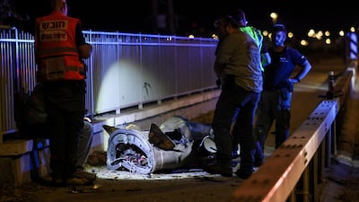 Israeli security and rescue personnel work next to a part of a projectile following a missile attack from Iran in northern Israel on Monday. Reuters