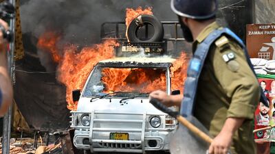 A van burns during clashes between supporters of former Pakistani prime minister Imran Khan and riot police near Khan's house to prevent officers from arresting him, in Lahore. AFP