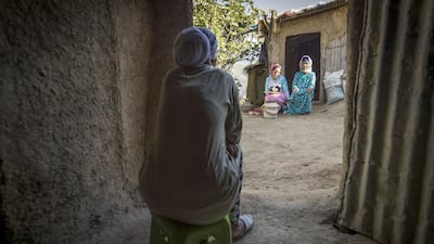 A neighbour watches as Moroccan potter Houda Oumal, sitting next to her mother Fatima Harama, paints with natural pigments on one of her pieces of pottery. AFP