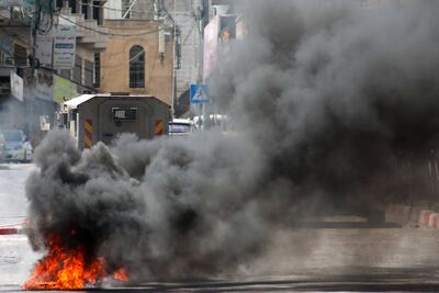 Smoke billows from burning tyres behind an Israeli army vehicle in the occupied West Bank city of Hebron on July 31, 2024, during a demonstration by Palestinians denouncing the killing of Hamas leader Ismail Haniyeh. AFP