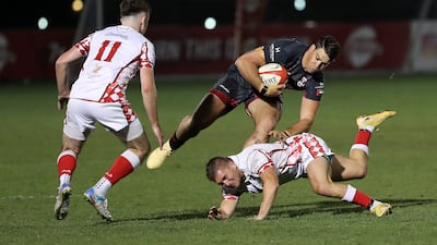 A Dubai Exiles player attempts to avoid a tackle from Abu Dhabi Harlequins.