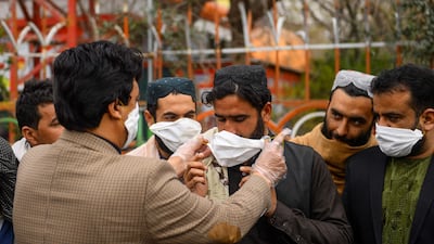 A volunteers (L) hands out free facemasks to people as a preventive measure against the spread of the coronavirus, in Herat city. AFP