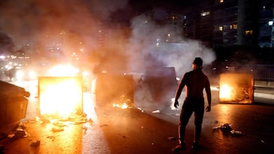 A supporter of Lebanese Prime Minister Saad Hariri burns garbage containers to block a main road, in Beirut, Lebanon. AP Photo