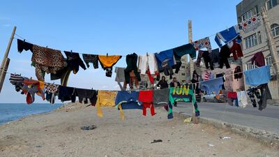 Palestinians walk as laundry hangs on a rope along the beach at Shati refugee camp in Gaza city. Reuters
