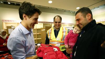 Syrian refugees are presented with a child's winter jacket by Canada's prime minister, Justin Trudeau, (L) on their arrival from Beirut at the Toronto Pearson international airport in Mississauga on December 11, 2015. Mark Blinch/Reuters