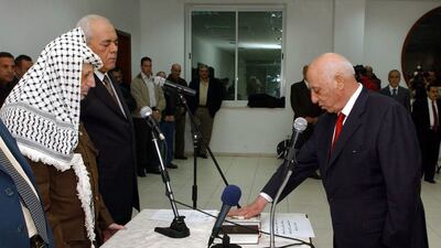 Mr Arafat watches as Mr Qurei swears allegiance on the Quran in November 2003. Getty