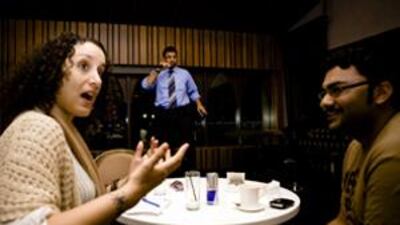 The aspiring comedian Zulfiqar Ali takes up the microphone while Mina Liccione and Ali al Sayed, the hosts of Monday Night Funnies, listen and appraise his performance.