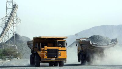 Two trucks cross at rock quarry as a crusher machine in the rear empties rocks near Fujairah. Andre Forget / The National