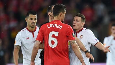 Liverpool’s Croatian defender Dejan Lovren, centre, talks to Sevilla’s French forward Kevin Gameiro, right, after receiving a yellow card. Paul Ellis / AFP
