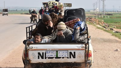 Civilians fleeing the city of Afrin in northern Syria are seen on the back of a pick up truck as they enter the village of Tal Rifaat in the government-controlled part of the northern Aleppo province, on March 18, 2018. George Ourfalina / AFP