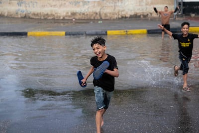 Iraqi boys play in a pool of water in the street, a day after heavy rain in Basra. AFP
