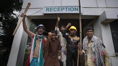 Pakistani protesters hold sticks and chant slogans after intruding the state television building in Islamabad, Pakistan. Anjum Naveed / AP