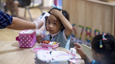 A staff member checks the tempertaure of a pupil at British International School Abu Dhabi. All photos by Victor Besa / The National