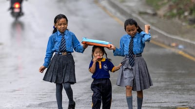 Girls protect their younger sister from the rain during monsoon season in Kathmandu, Nepal. EPA