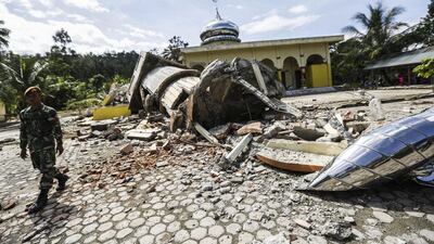 An Indonesian soldier inspects a collapsed mosque after the earthquake. Hotli Simanjuntak / EPA