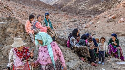 Survivors sit on rocks on the side of a hill. AFP