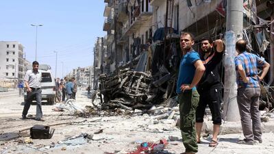 Syrians stand next to debris following bombardment by government forces on the Salhin district of the northern city of Aleppo on July 21, 2016. The United Nations on THursday issued an urgent plea for weekly 48-hour truces in Aleppo, where at least a quarter of a million civilians are now trapped by a government siege. Thaer Mohammed/AFP