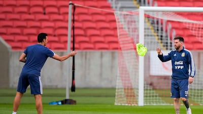 Argentina manager Lionel Scaloni throws a vest to Lionel Messi during a training session. AFP
