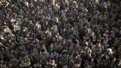 During the festival, men, women and children — some covered with capes from head to foot, eyes peering from a cake of mud on their faces — collect candles from bystanders along the village’s main street on their way to St John the Baptist’s Church. Bullit Marquez / AP Photo