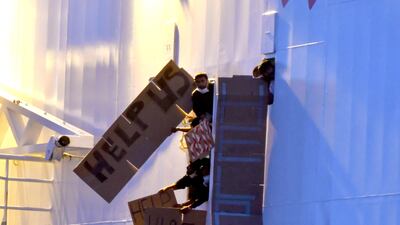 Migrants hold signs from aboard the charity ship 'Geo Barents' off Catania, Sicily, on Monday. EPA