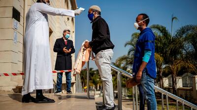 A man has his temperature checked at the entrance of the Nizamiye Mosque ahead of the Friday prayer in Midrand, Johannesburg. AFP