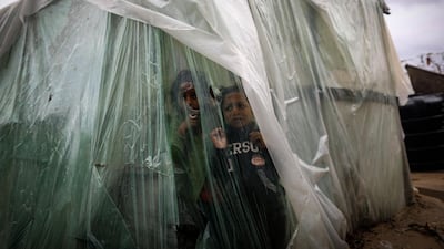 Palestinian children watch the rain from behind nylon sheets covering their family tent, on a rainy day in al-Amal (hope in Arabic) neighbourhood of Beit Lahia in the northern Gaza Strip. AFP