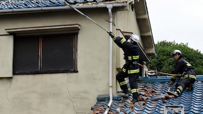 Firefighters try to remove debris on the damaged roof of a house, after a magnitude 6.1 earthquake in Osaka. EPA
