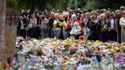 Mourners view the flowers. AFP