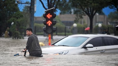 A man struggles with his bike on a flooded road after record downpours in Zhengzhou city in central China's Henan province.