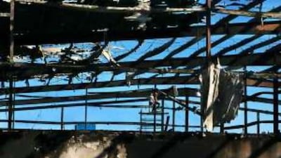 Workers demolish the roof of a building that was damaged by the fire int he Fujairah Free Zone.