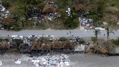 People walk down the street next to destroyed houses in Jeremie. At least 23 people were killed in Haiti, a toll likely to climb as authorities re-establish contact with the hardest-hit areas Carlos Garcia Rawlins / Reuters