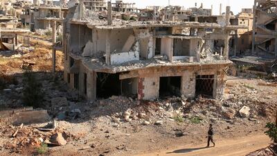 A fighter walks past damaged buildings in southern Syria (REUTERS/Alaa Al-Faqir/File Photo)