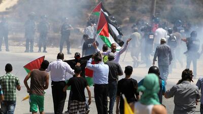 Palestinian protesters walk with flags in front of Israeli forces after a demonstration in the West Bank village of Nabi Saleh near Ramallah. Abbas Momani / AFP Photo